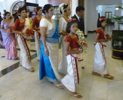 Bride, her mother and attendants walk towards ceremonial room