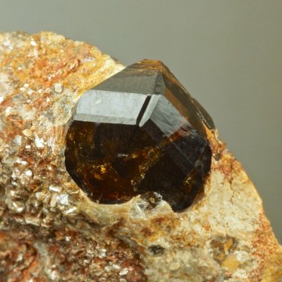 Lustrous sharp 1 cm geniculate twin of cassiterite on mica schist. Merekski ore district, Burea Massif, Khabarovskiy Kray, Far-e