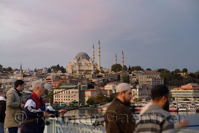Turkish men fishing on Galata Bridge over Golden Horn with Suleymaniye Mosque Istanbul