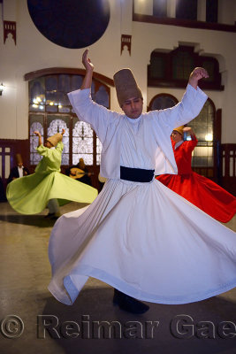 Male Sufi Whirling Dervish in white at a Sema Ceremony with musicians and women at Istanbul train station