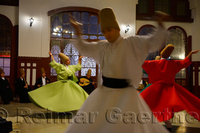 Spinning male and female Whirling Dervishes in a Sema Ceremony with musicians at Istanbul train station