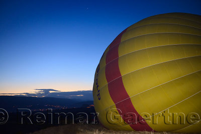 The lights of Urgup and planet Venus at dawn with hot air balloon being inflated with a fan in Cappadocia Turkey
