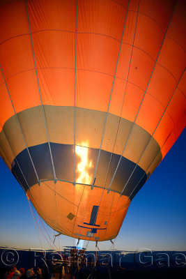 Propane heater inflating a hot air balloon at dawn with Urgup city lights Cappadocia Turkey