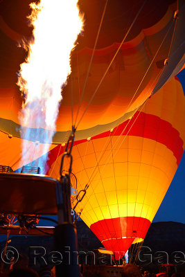 Red glow of blasts from propane heaters inflating hot air balloons at dawn Cappadocia Turkey
