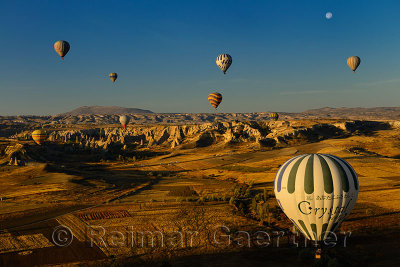 Love Valley and farm fields at dawn Cappadocia Turkey with hot air balloons and moon