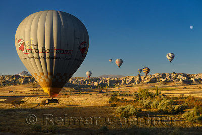 Hot air balloon landing in farm fields at Love Valley and Uchisar Cappadocia Turkey with moon