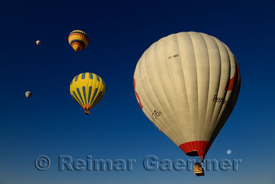 Hot air balloons against a blue sky with moon in Cappadocia Turkey