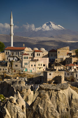 Houses and Mosque in Ortasihar with view of Mount Erciyes and tuff hoodoos Cappadocia Turkey