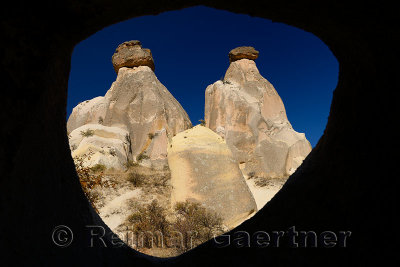 View of two Fairy Chimneys with sphynx on the left through a window of a cave Urgup Turkey