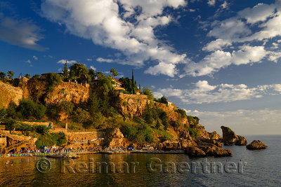 Cliffside resort and beach on Turkish Riviera at Antalya Kaleici Harbour Turkey at sunset