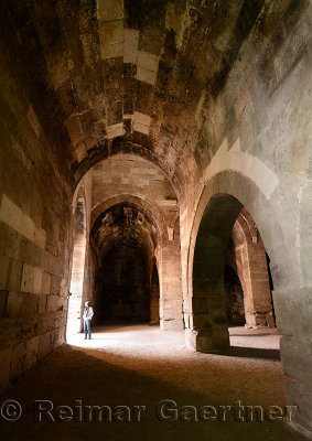 Tourist standing under stone arches of Sultanhani Caravanserai enclosed storage and winter accomodation area Turkey