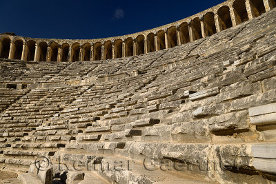 View of semicircular stone seats at ancient Aspendos theatre from the stage with upper gallery arches in Turkey