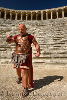 Roman Gladiator with sword in sun on stage at the ancient Aspendos theatre Turkey