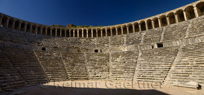 Panorama of semicircular stone seats at Aspendos Amphitheatre with upper gallery arches and stage Turkey