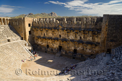 View of Aspendos theatre stage facade and distant hills from upper gallery with groups of tourists in Turkey