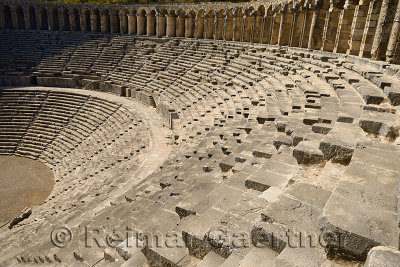 Semicircle of stone seats at Aspendos Amphitheatre with upper gallery arches and stage Turkey