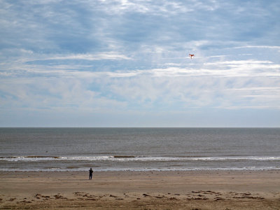 A lonely figure flying a kite