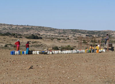 Lining up at the well to fill their water containers.