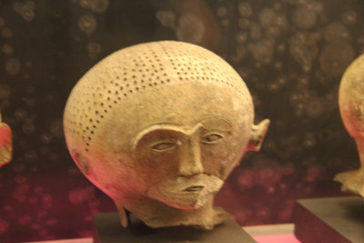 Anthropomorphic burial jar of unpainted head with perforations and partition at the center.