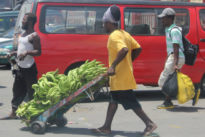 A vendor hauling a cart of bananas.