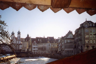 View from inside the Chapel Bridge of the Reuss River and of buildings along its banks.