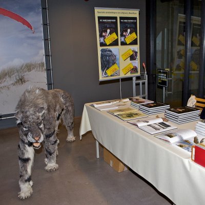 De Sabeltandkat kijkt toe bij de stand van uitgeverij Drukware waar zijn boek verkocht wordt tegen een aantrekkelijke prijs