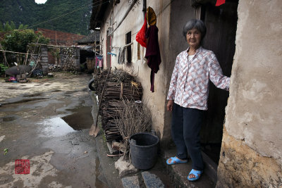 Farm lady outside her house in a village in Xing Ping.