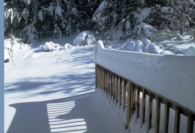 Snow balancing act on the deck railing.
