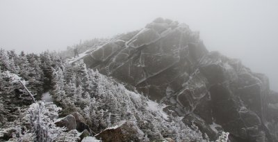A hiker starts up the rocky summit cone of Mt. Liberty in the fog.
