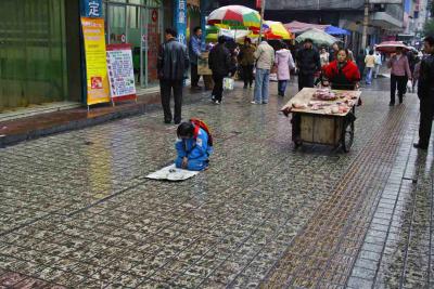 Begging, sidewalk wet and muddy.