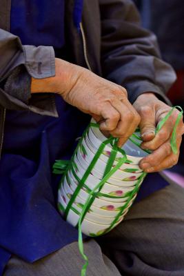 Man bundling bowls after sale in streetside sale. Dali, China.