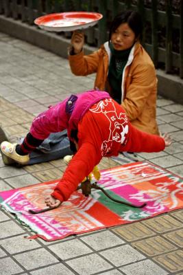 Girl spinning while balancing on mouth. Jishou City, China.