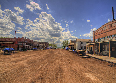 A long shot of  main street showing the paved street covered with dirt.