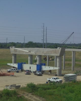 The shaped piece with the blue tarps will be raised and fitted into the concrete structure