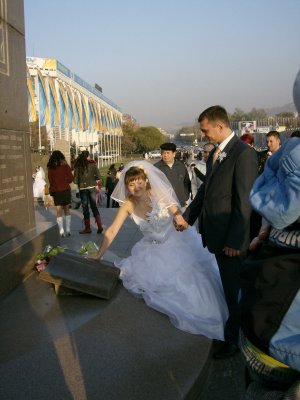 Bride places her hand into the Nazarbayev palm print in the Independence Book at the foot of the column