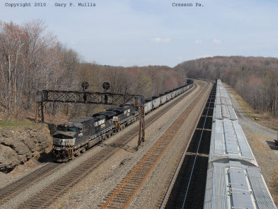 Westbound hoppers under a PRR signal bridge at Cresson. A grain train is parked in a siding.jpg