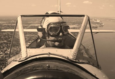 My adopted son Denis piloting the Stearman over the Detroit River.  Taken blind as I am harnessed in.  Turn the camera around, point and hope.  Though the sepia treatment would give it the look of the early days of aviation.
 
