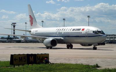 Air China 737-800, note a airport worker hiding in front of the taxi way sign