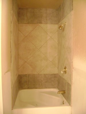 Instead of the previous white (with design) wall board around the shower walls, we removed it and had large 16x16 tiles put in.  