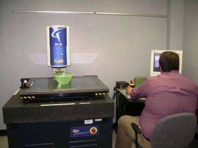 This Flash machine is like a scanner of sorts, and it slides the object under the blue canister area camera, which then feeds to the computer that is being manned.  This part of the QA area is to ensure the product is the exact size & dimensions that it is described to be.