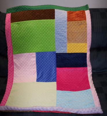 The material I used to make this Gracie's Quilt of Many Colors is called minky chenelle.  It is incredibly soft!!!  I used remnants given to me from a (new) friend.  The blanket is rectangle although the way it's laying on the couch makes it appear hour-glass.