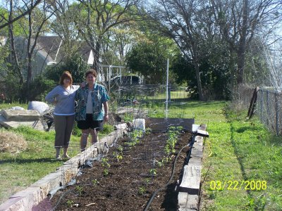 Looking down the opposite end at both of us.  While she was getting the grass roots out on her end, I was pulling simpler weeds on the other end, then planting this year's tomato and pepper bushes.  Here we are posing by what we hope will be a bountiful harvest this year.