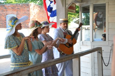 Singers entertain queueing riders with period songs and costumes.