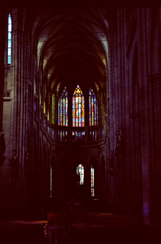 Inne i katedralen, et dunkelt rom opplyst av glassmalerier