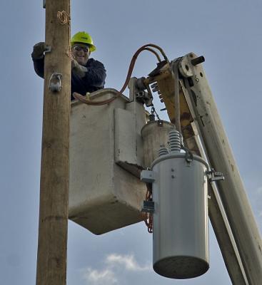 Utility worker putting up a new power pole