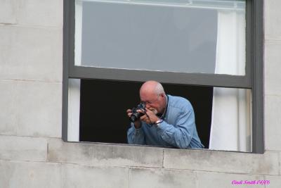 GUY IN A BUILDING TAKING SHOTS OF THE GATHERING