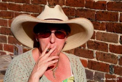 PAM WITH HER HAT ON ENJOYING A CIGAR