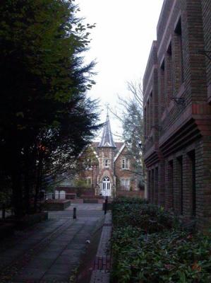 A churchlike apartment house nestled in between carparks and businesses.