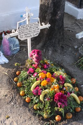 The grave is adorned with bananas and oranges as well as flowers.