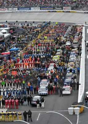 DRIVERS AND CREWS STAND AT ATTENTION DURING THE NATIONAL ANTHEM